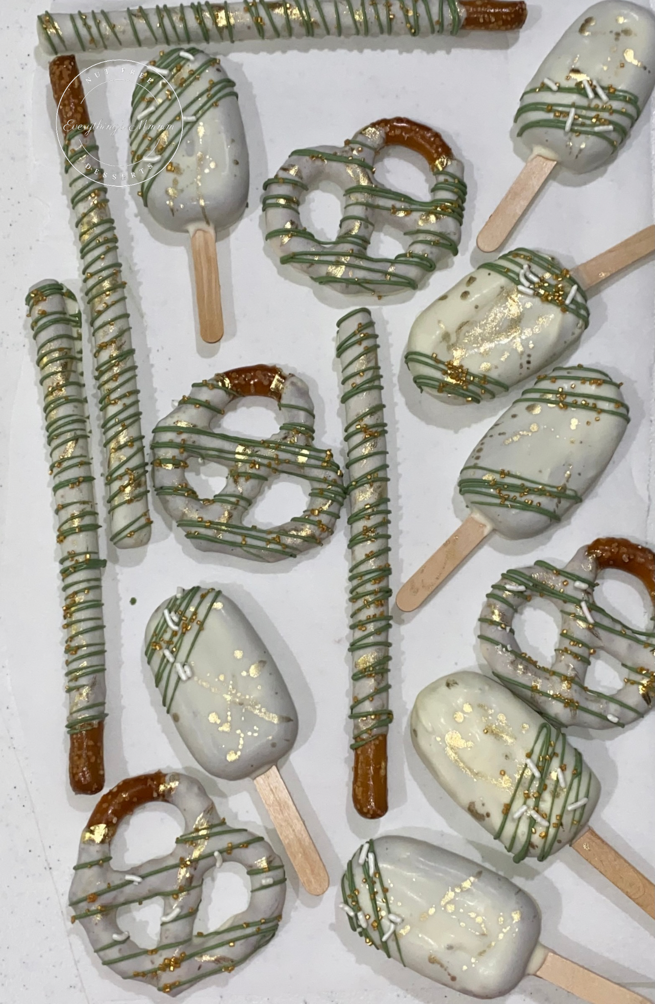 Decorative pretzels and cakesicles with gold and silver accents on a white background